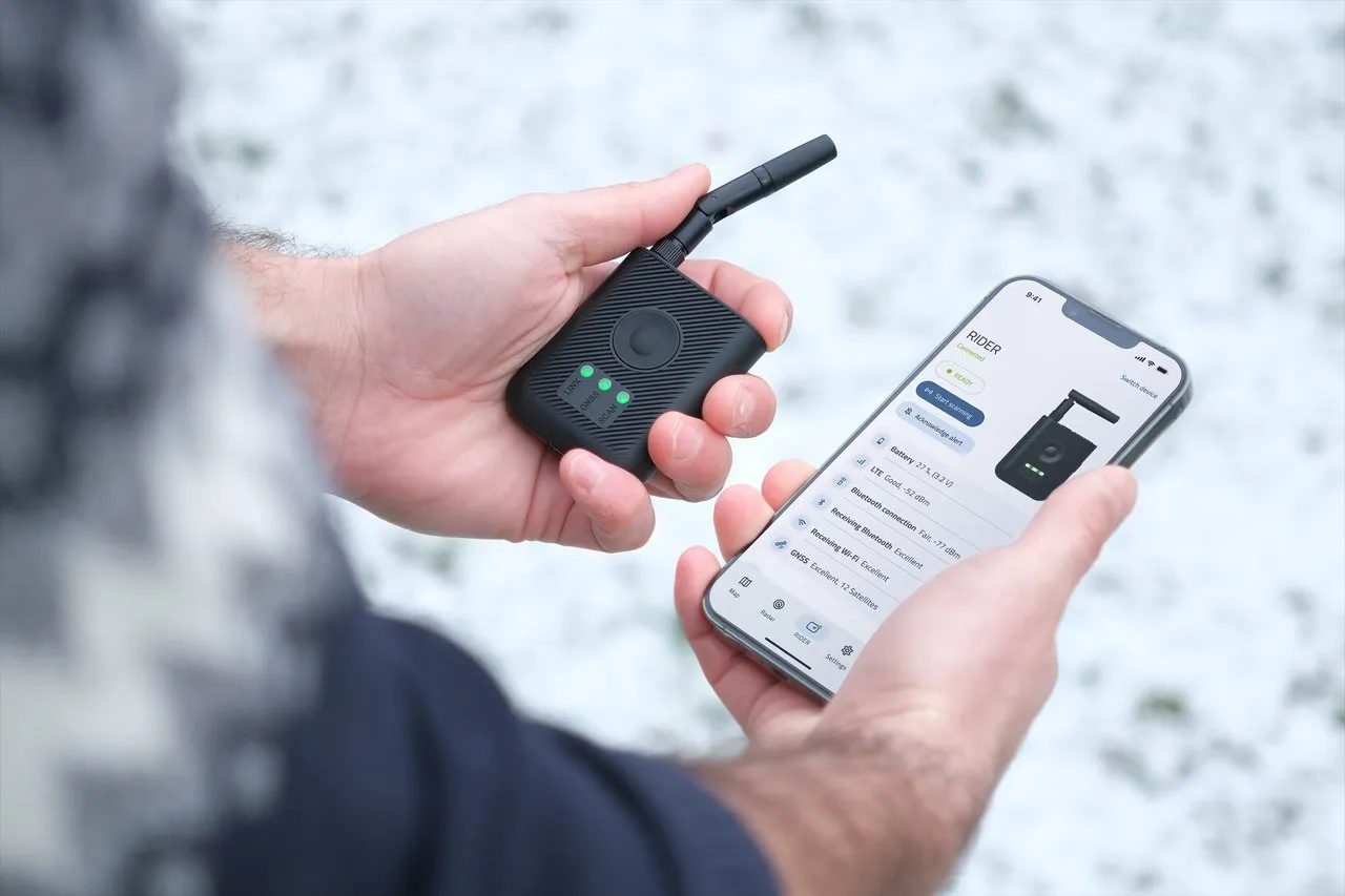 A handheld receiver held next to a phone showing a drone on a map